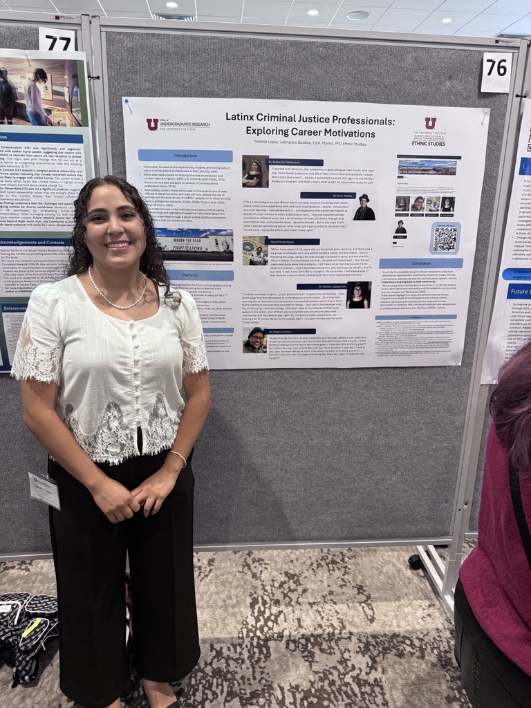 A student stands next to a research poster titled "Latinx Criminal Justice Professionals: Exploring Career Motivations"